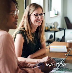 Two women sitting at a desk looking at a computer